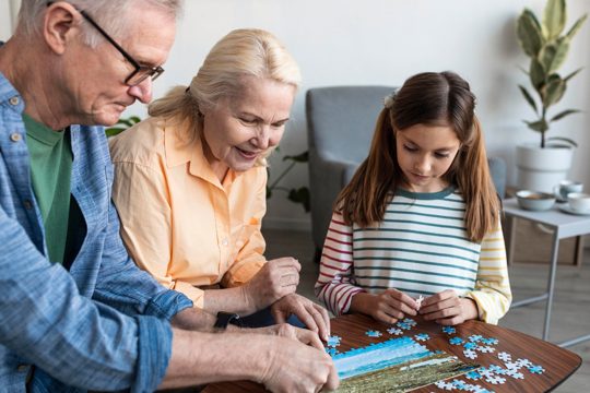 Grandparents and girl doing puzzle close up