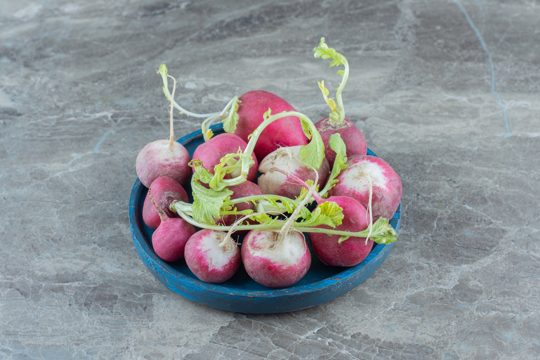 Delectable radishes in the bowl , on the marble table.