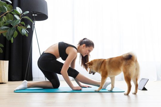 Young woman doing yoga next to her dog