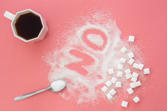 Word no made of sugar and cup of coffee on pink background flat lay