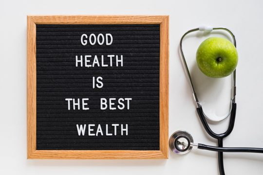 Good health message board with green apple and stethoscope on white background