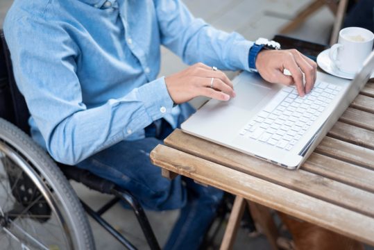 Close-up disabled man typing on laptop