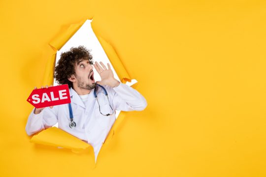 Front view male doctor in medical suit holding sale writing calling someone on yellow color shopping health medicine hospital medic