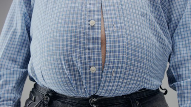 Overweight man in shrt is small to him with huge belly and open buttons