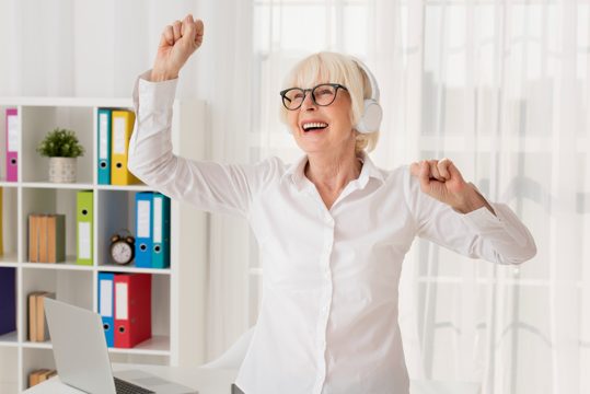 Elder woman listening music in her office