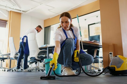 Professional cleaning service person using vacuum cleaner in office