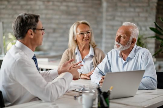 Mature couple meeting bank manager and communicating with him during consultations in the office