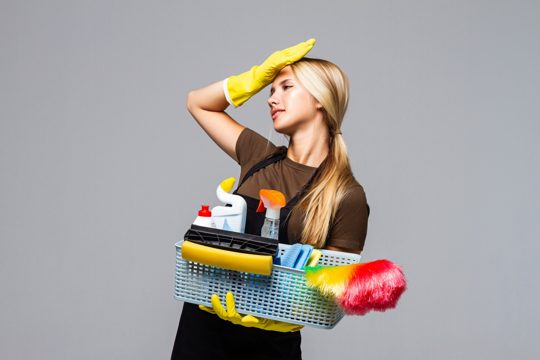 Young attractive housewife wearing casual clothes, latex gloves holding full basin of cleaning agent isolated on white