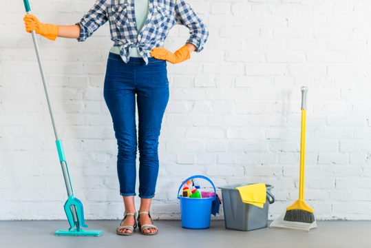 Woman standing in front of brick wall with cleaning equipments