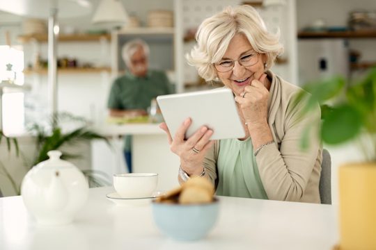 Happy mature woman using digital tablet at home