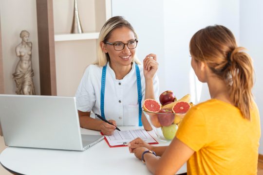 Female nutritionist giving consultation to patient making diet plan in weight loss clinic