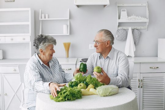 Beautiful old couple prepare food in a kitchen