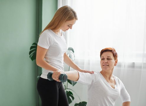 Elder woman in covid recovery doing physical exercises with dumbbell