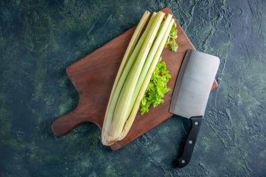 Top view fresh green celery with big knife on dark blue background salad health diet food meal color photo