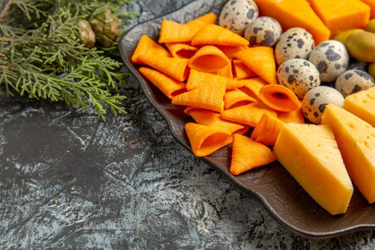 Side view of tasty best snack for wine on brown tray and fir branches on ice background