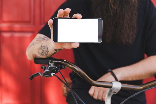 Young man with bicycle showing mobile phone screen