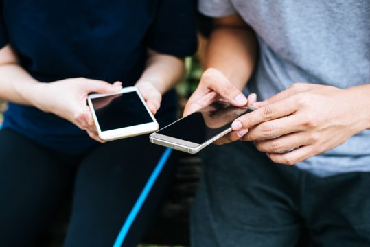 Close up of friends hands play with smartphone together.