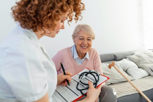 Senior woman is visited by her doctor or caregiver female doctor or nurse talking with senior patient medicine age health care and home care concept senior woman with her caregiver at home