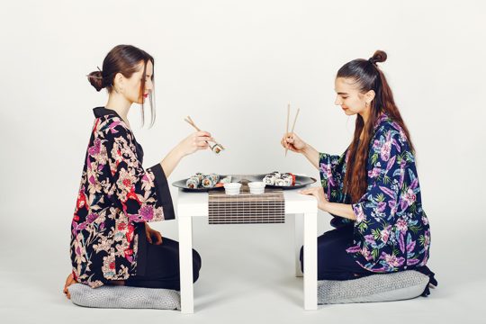 Beautiful girls eating a sushi in a studio