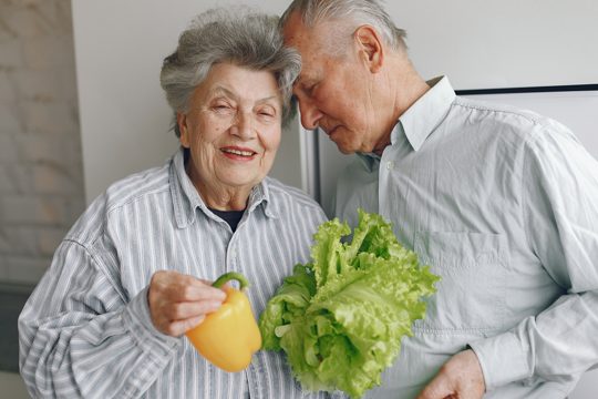 Beautiful old couple prepare food in a kitchen