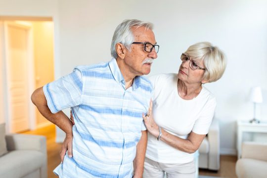 Senior couple at homeelderly man is having back pain and his lovley wife supports him