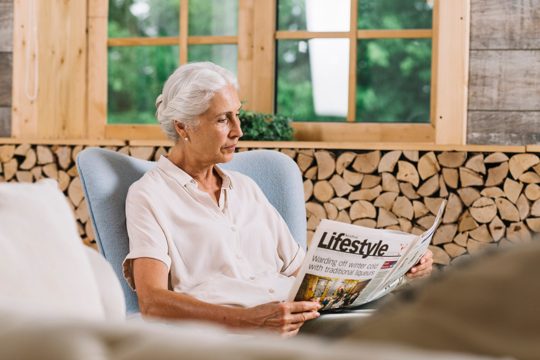 Close-up of woman sitting on chair reading newspaper