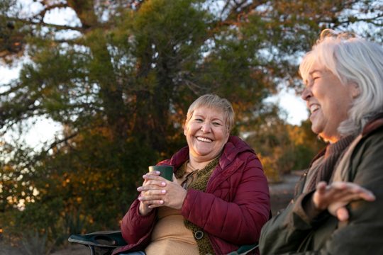 Two senior women on a nature escapade sitting on chairs and enjoying their time