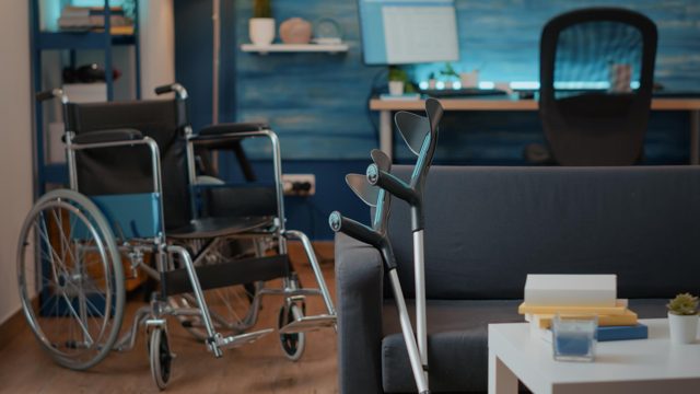 Nobody in living room with wheelchair and crutches to help with transportation. empty space with walking support equipment to give aid to people with chronic disability. physical mobility